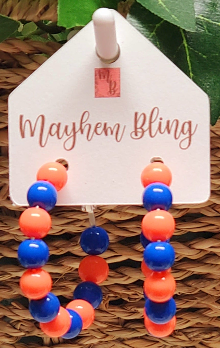 Colorful beaded earrings on a 'Mayhem Bling' branded card with green leaves in the background
